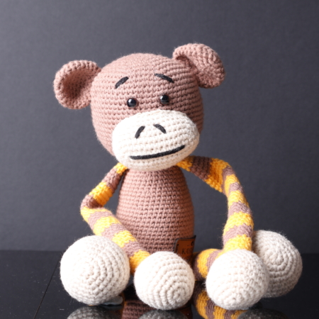 Handmade amigurumi monkey toy with extra-long arms, ideal for baby room decor or as a curtain tie-back holder. Crafted with soft yarn in shades of brown and beige, with embroidered eyes and a friendly smile